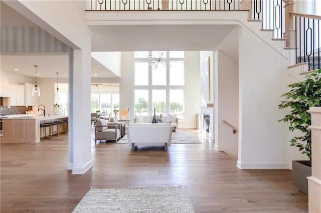 2461 W 176th St, Overland Park, KS 66085 - living room featuring a notable chandelier, a towering ceiling, baseboards, stairway, and light wood-style flooring