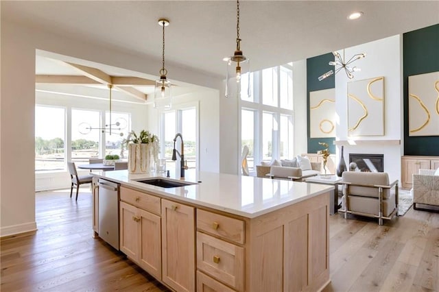 kitchen featuring a center island with sink, light wood-type flooring, dishwasher, light brown cabinetry, and sink