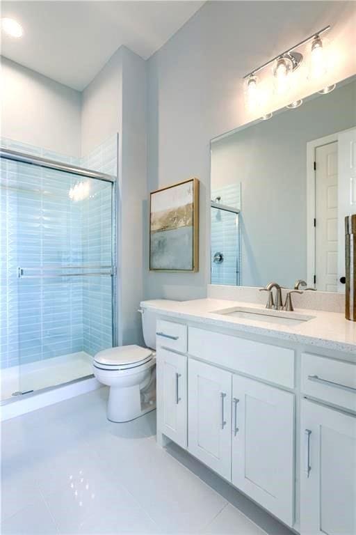 bathroom with an enclosed shower, tile patterned floors, vanity, and toilet