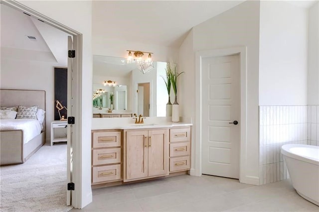 bathroom with a washtub, vanity, and tile patterned flooring