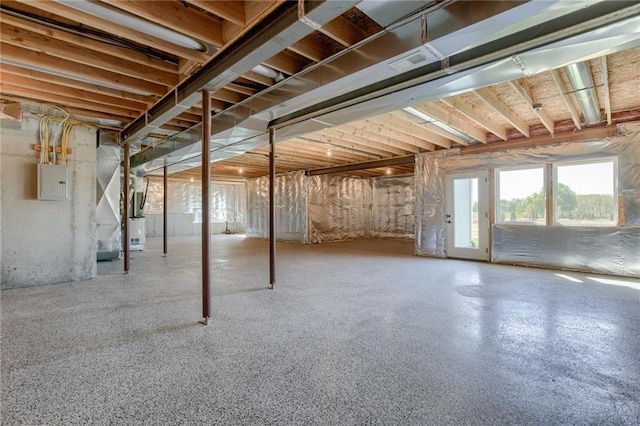 basement featuring electric panel and heating unit