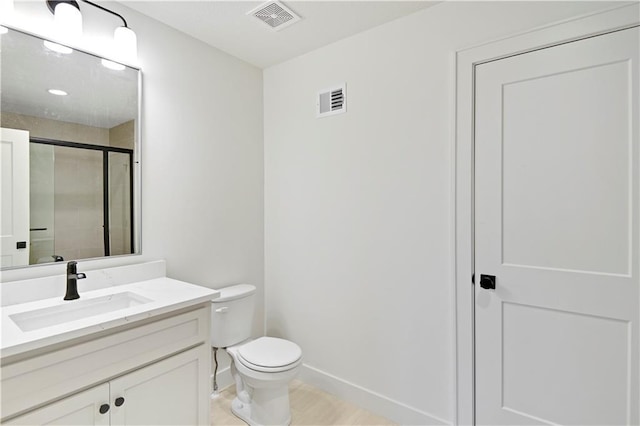 bathroom with vanity, toilet, and a shower with shower door