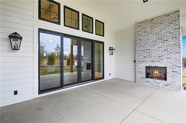 exterior space featuring an outdoor brick fireplace and a patio