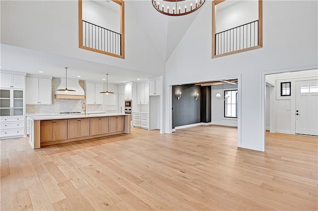 kitchen featuring a spacious island, custom exhaust hood, a chandelier, and white cabinets