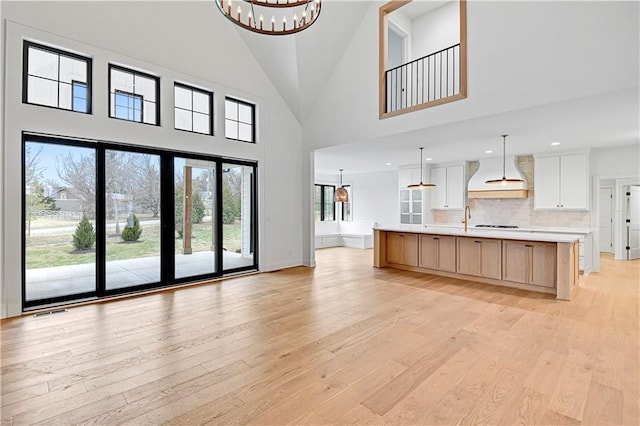 unfurnished living room with a notable chandelier, sink, and light wood-type flooring