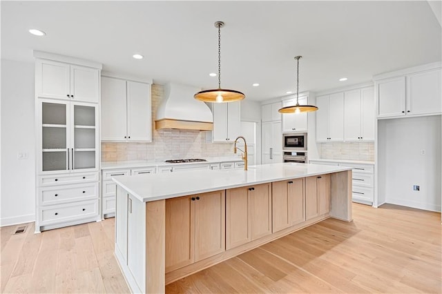 kitchen featuring premium range hood, a large island, and white cabinets