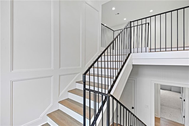 staircase featuring a high ceiling and hardwood / wood-style floors