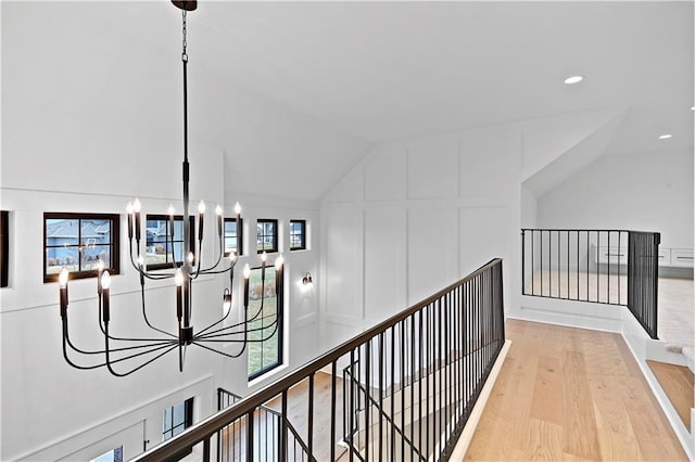 hall featuring a chandelier, vaulted ceiling, and light hardwood / wood-style flooring