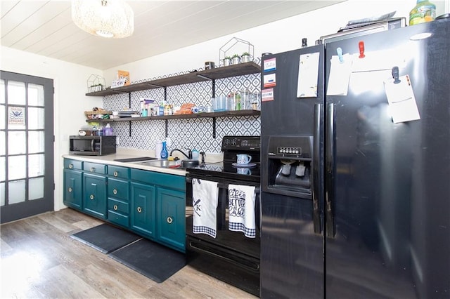 kitchen with blue cabinetry, sink, decorative backsplash, black appliances, and light wood-type flooring