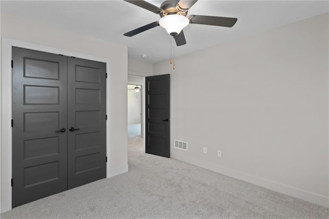 unfurnished bedroom featuring light carpet, a closet, and ceiling fan