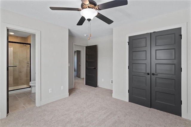 unfurnished bedroom with light colored carpet, a closet, and ensuite bathroom