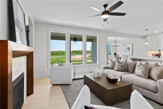 living room featuring ceiling fan with notable chandelier and light hardwood / wood-style floors