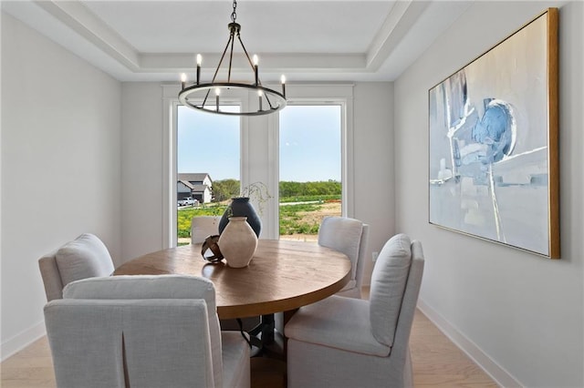 dining room with an inviting chandelier, light hardwood / wood-style flooring, and a tray ceiling