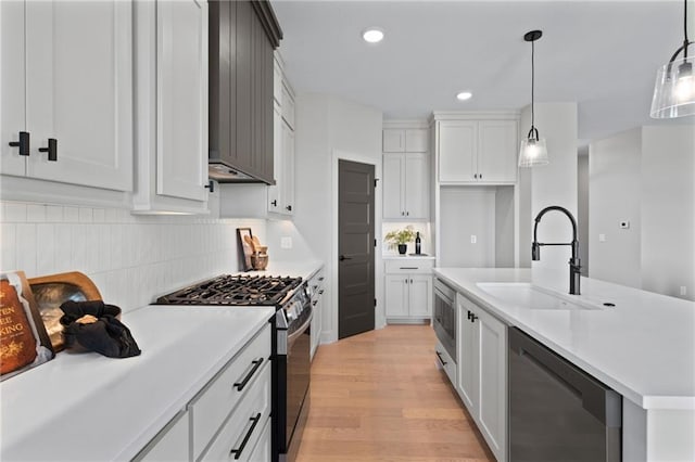 kitchen featuring appliances with stainless steel finishes, sink, tasteful backsplash, light hardwood / wood-style flooring, and premium range hood