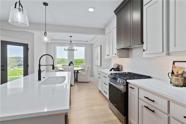 kitchen featuring light hardwood / wood-style floors, tasteful backsplash, stainless steel range with gas cooktop, and a wealth of natural light