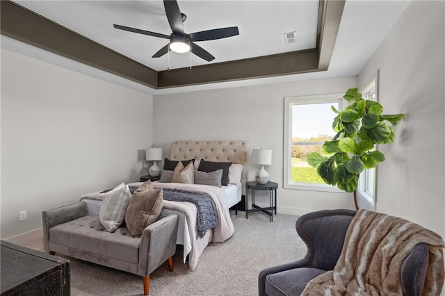 bedroom with ceiling fan, carpet, and a raised ceiling