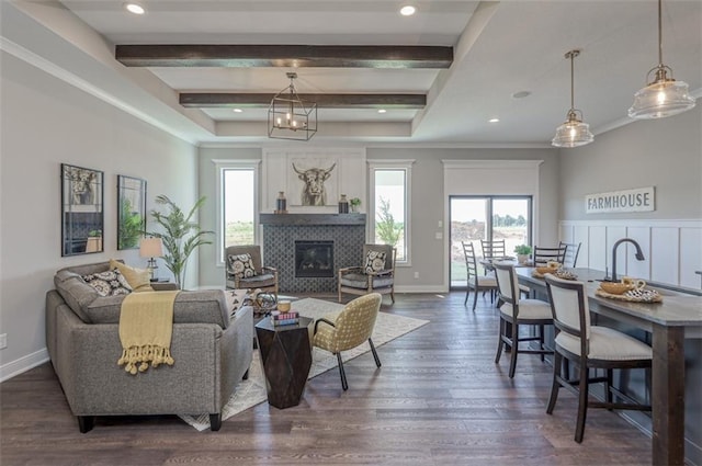 living room featuring beam ceiling, a tiled fireplace, and dark hardwood / wood-style floors