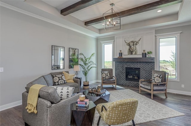 living room featuring a tiled fireplace, a wealth of natural light, dark hardwood / wood-style flooring, and an inviting chandelier