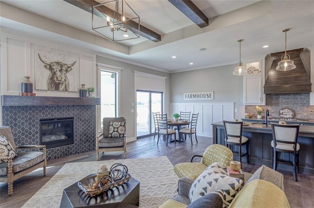 living room featuring beam ceiling, crown molding, a fireplace, and dark hardwood / wood-style floors