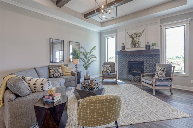 living room featuring a tile fireplace, hardwood / wood-style flooring, and a notable chandelier