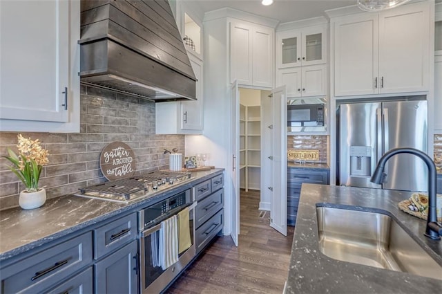 kitchen featuring custom exhaust hood, stainless steel appliances, sink, blue cabinetry, and white cabinetry