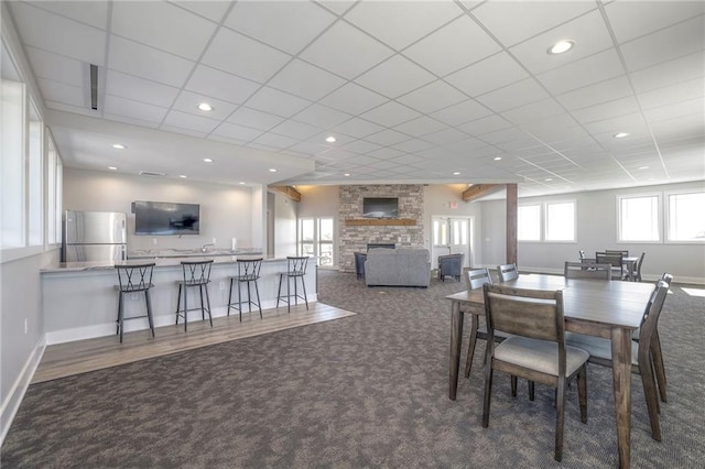 carpeted dining room with a stone fireplace