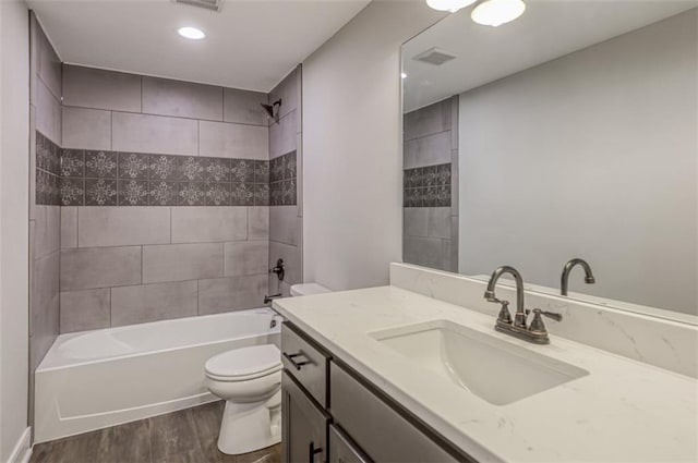 full bathroom featuring hardwood / wood-style flooring, tiled shower / bath combo, toilet, and vanity