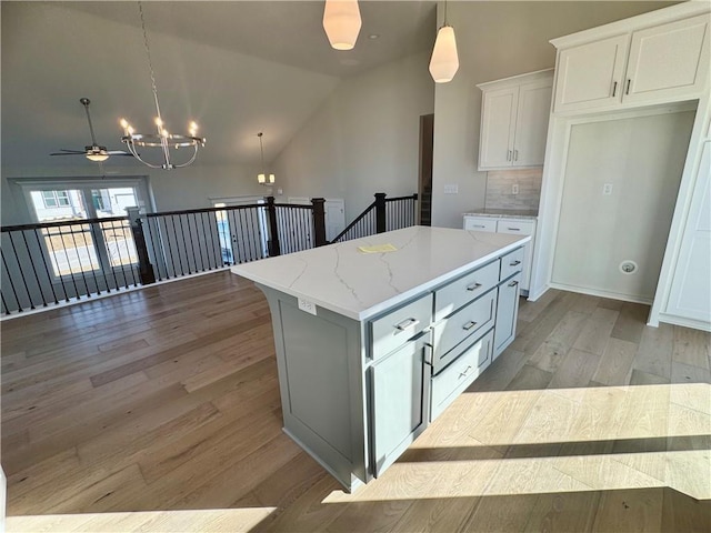 kitchen featuring white cabinets, a center island, light hardwood / wood-style floors, and ceiling fan with notable chandelier