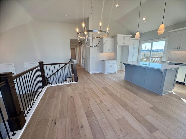 kitchen with white cabinetry, tasteful backsplash, pendant lighting, light hardwood / wood-style floors, and a kitchen island