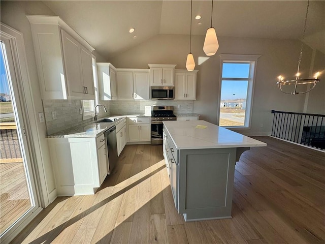 kitchen featuring pendant lighting, light hardwood / wood-style flooring, a kitchen island, white cabinetry, and stainless steel appliances