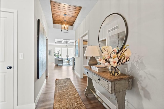 corridor featuring wood ceiling, an inviting chandelier, and dark wood-type flooring