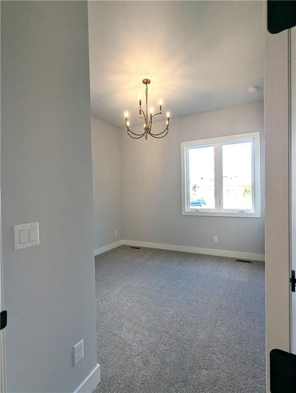 unfurnished room with a chandelier and carpet flooring