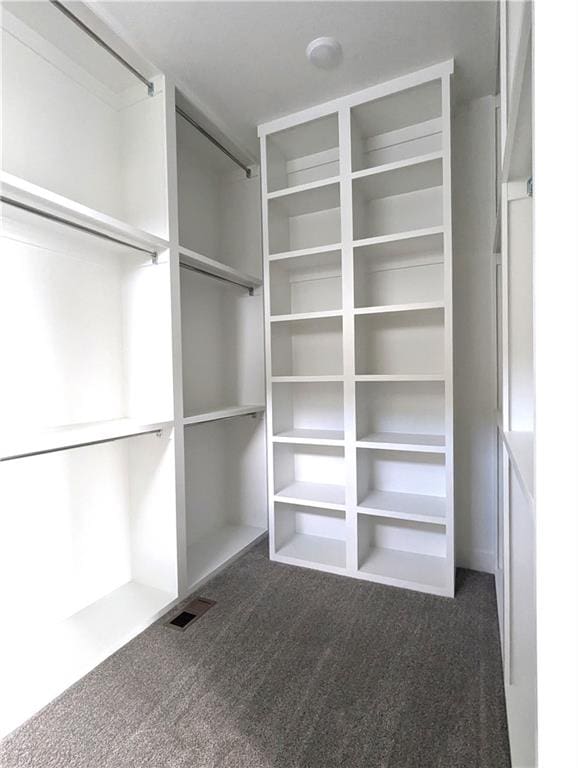 walk in closet featuring dark carpet