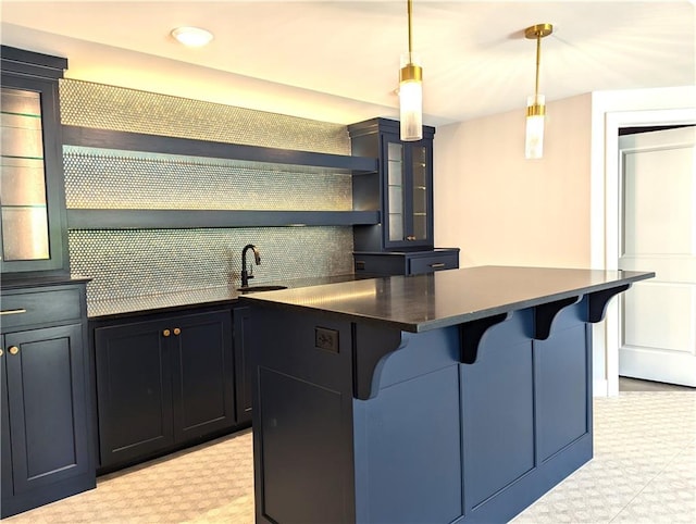 kitchen featuring decorative backsplash, hanging light fixtures, a kitchen island, a breakfast bar, and sink