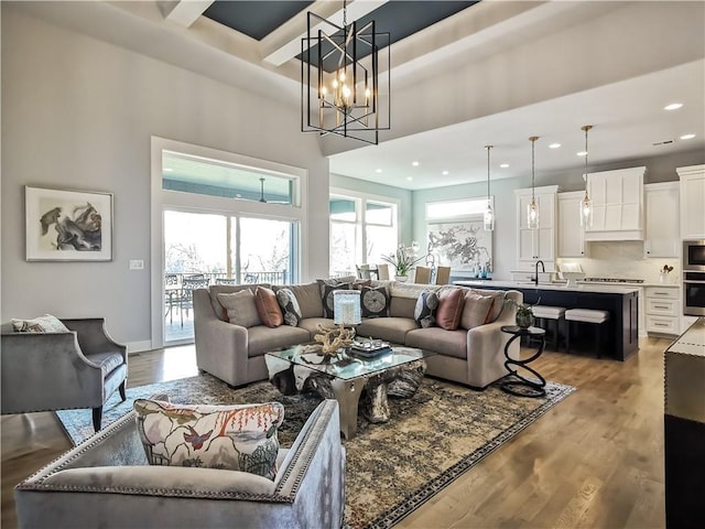 living room featuring sink, a chandelier, a high ceiling, and hardwood / wood-style floors