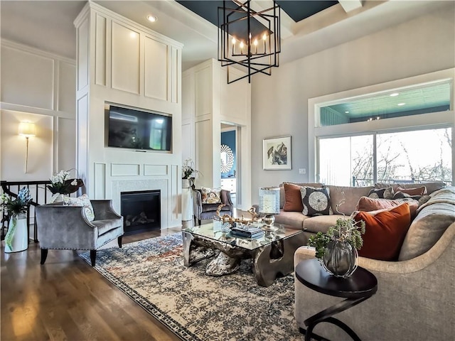 living room with a high ceiling, an inviting chandelier, and dark hardwood / wood-style flooring