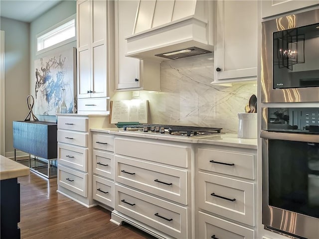 kitchen featuring tasteful backsplash, dark hardwood / wood-style flooring, stainless steel appliances, custom exhaust hood, and white cabinets