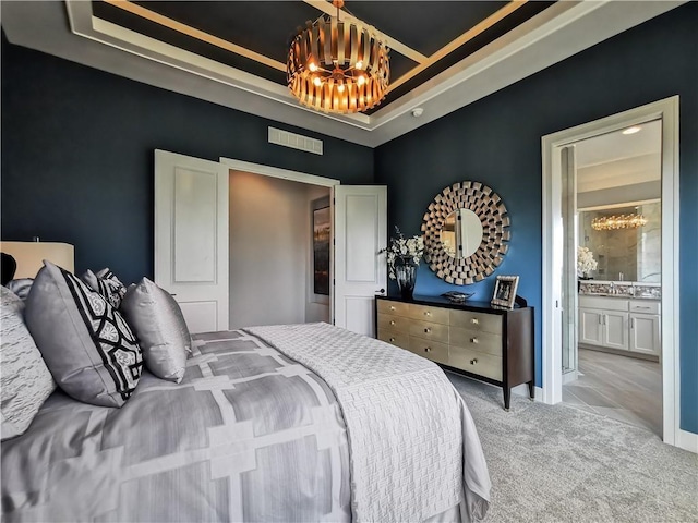 bedroom featuring light carpet, ensuite bath, sink, and a tray ceiling