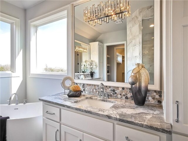 bathroom with vanity, backsplash, a bathtub, and plenty of natural light