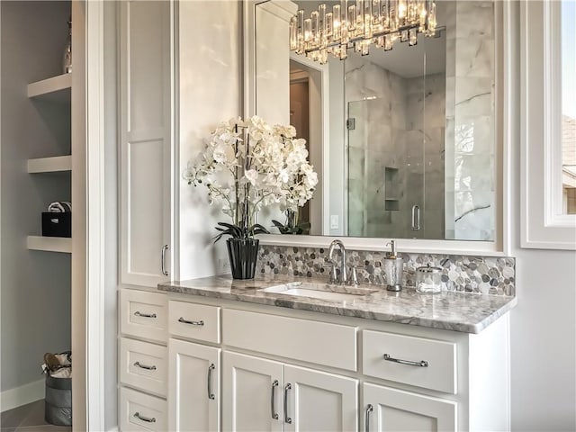 bathroom featuring a shower with door, decorative backsplash, and vanity