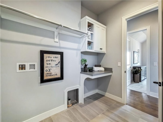 laundry area with hookup for a washing machine, light wood-type flooring, and cabinets