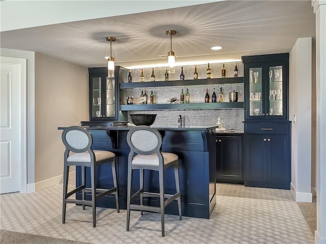 bar with blue cabinets, hanging light fixtures, and light colored carpet