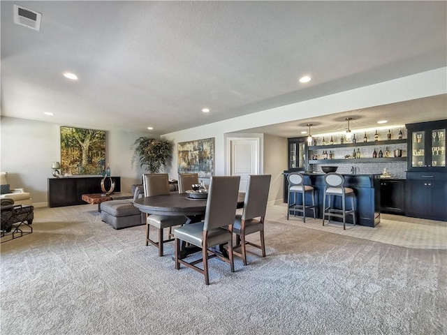 dining space with light carpet and indoor bar