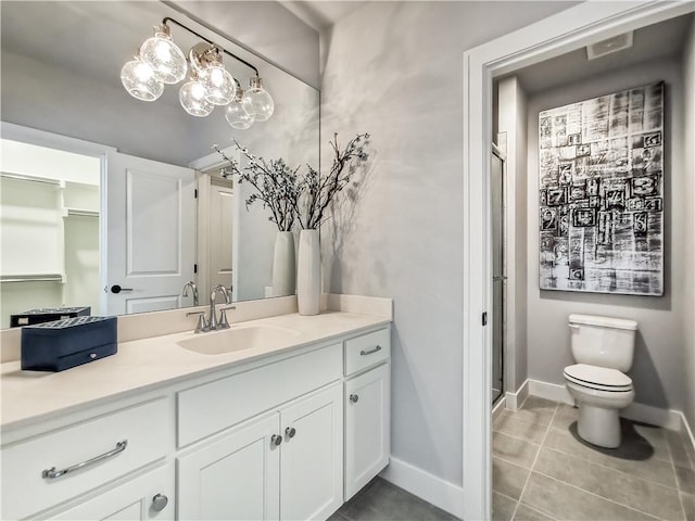 bathroom featuring a shower with door, toilet, vanity, and tile patterned flooring