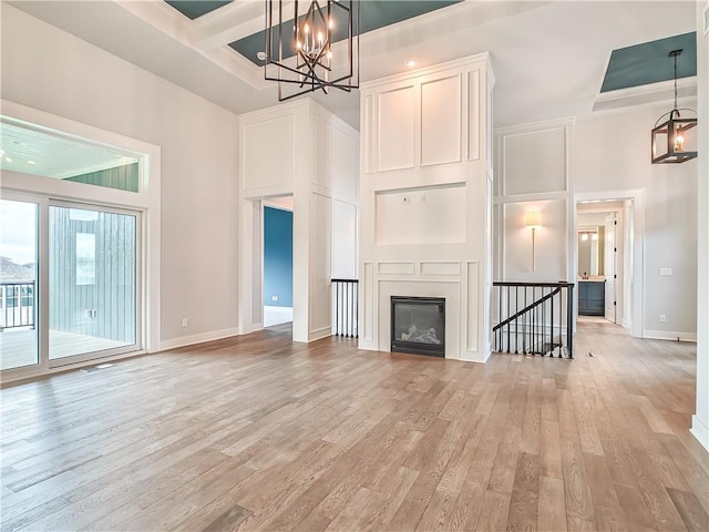 9301 W 168th St, Overland Park, KS 66085 - unfurnished living room with a chandelier, light wood-type flooring, coffered ceiling, baseboards, and beam ceiling