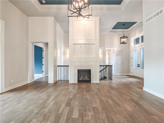 9301 W 168th St, Overland Park, KS 66085 - unfurnished living room with a tray ceiling, wood finished floors, a chandelier, baseboards, and a high ceiling