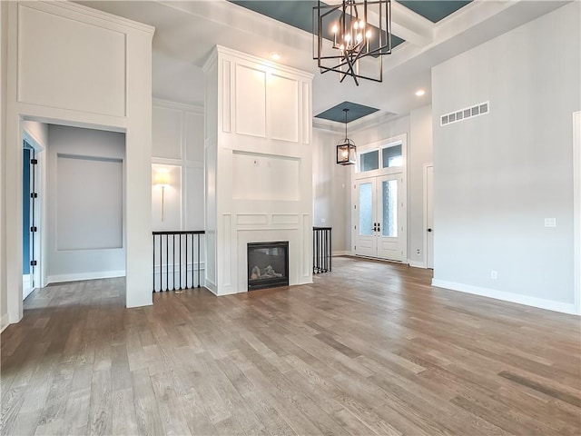9301 W 168th St, Overland Park, KS 66085 - unfurnished living room featuring a chandelier, light wood-style flooring, a high ceiling, baseboards, and coffered ceiling