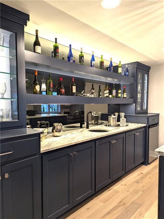 bar with light stone countertops and light hardwood / wood-style flooring