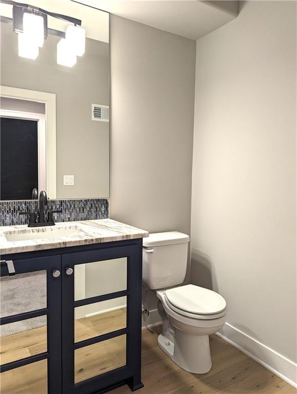 bathroom featuring wood-type flooring, vanity, and toilet