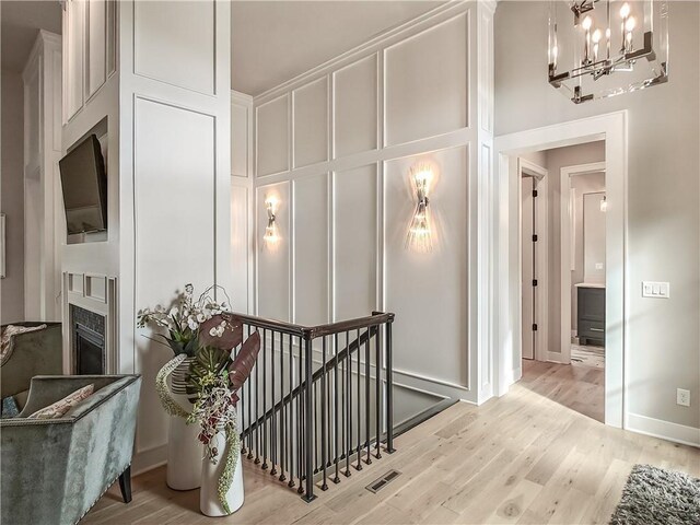16724 Hayes St, Overland Park, KS 66085 - stairs with wood finished floors, a chandelier, a fireplace, a decorative wall, and baseboards